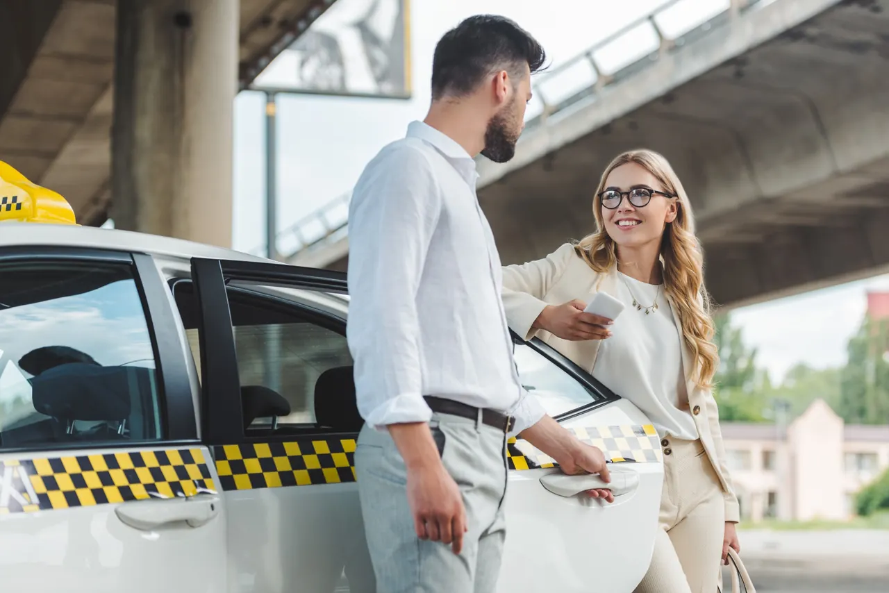 A man opening a taxi door for a passenger
