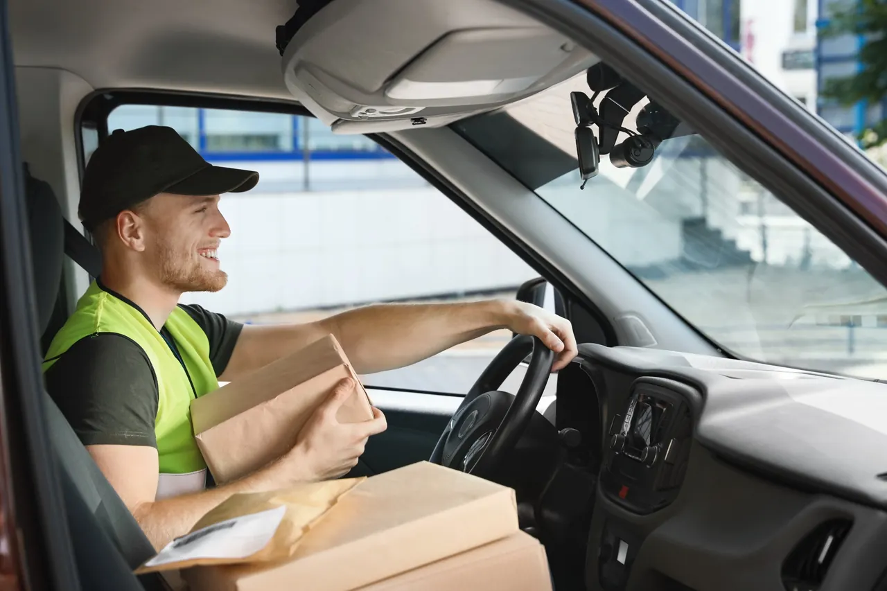 Courier with parcels beside a van