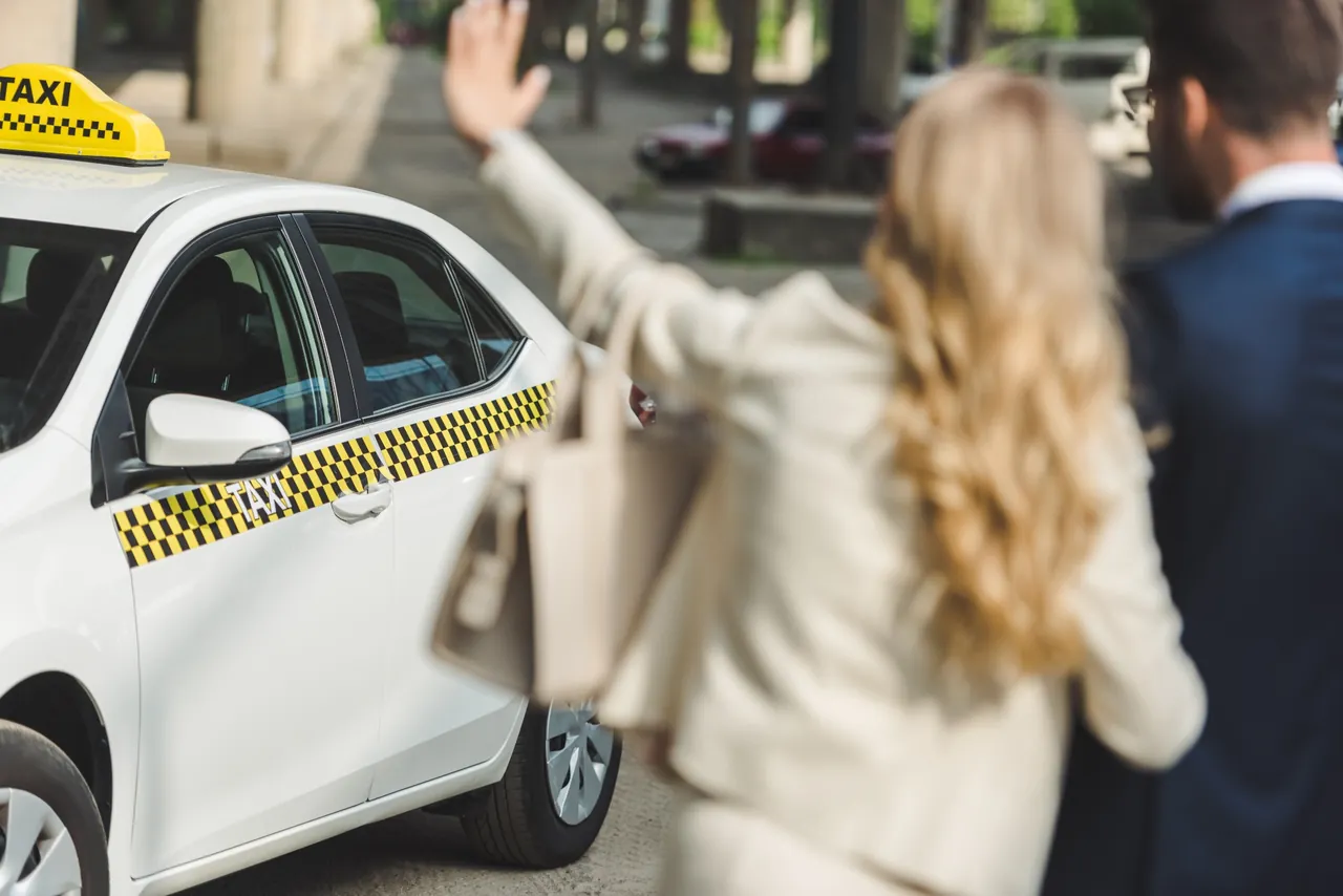 A passenger waving to a taxi in the city